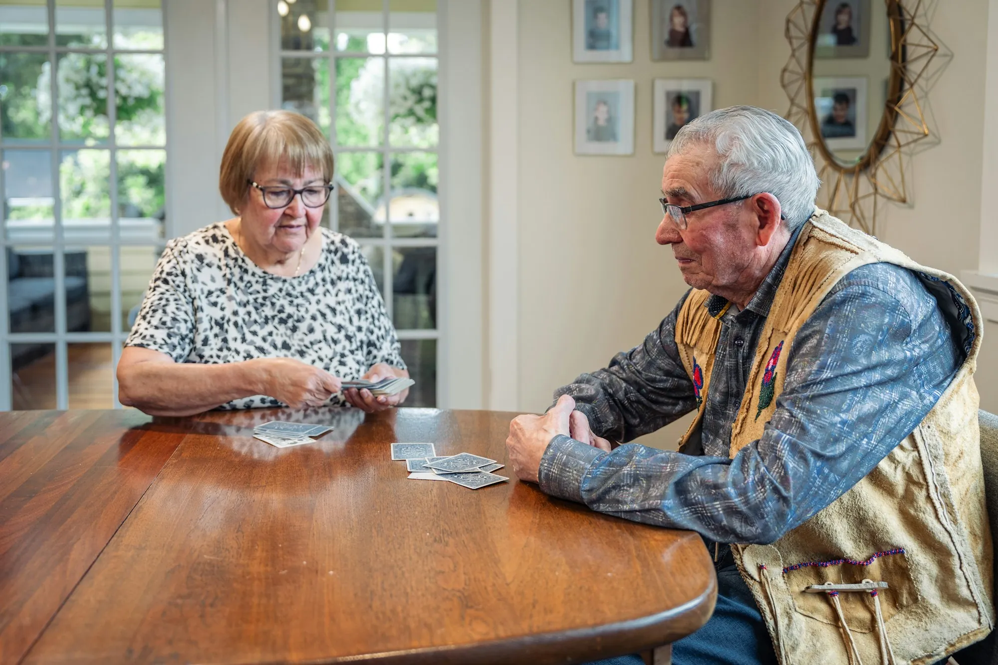 An older woman and an older man playing cards at a kitchen table