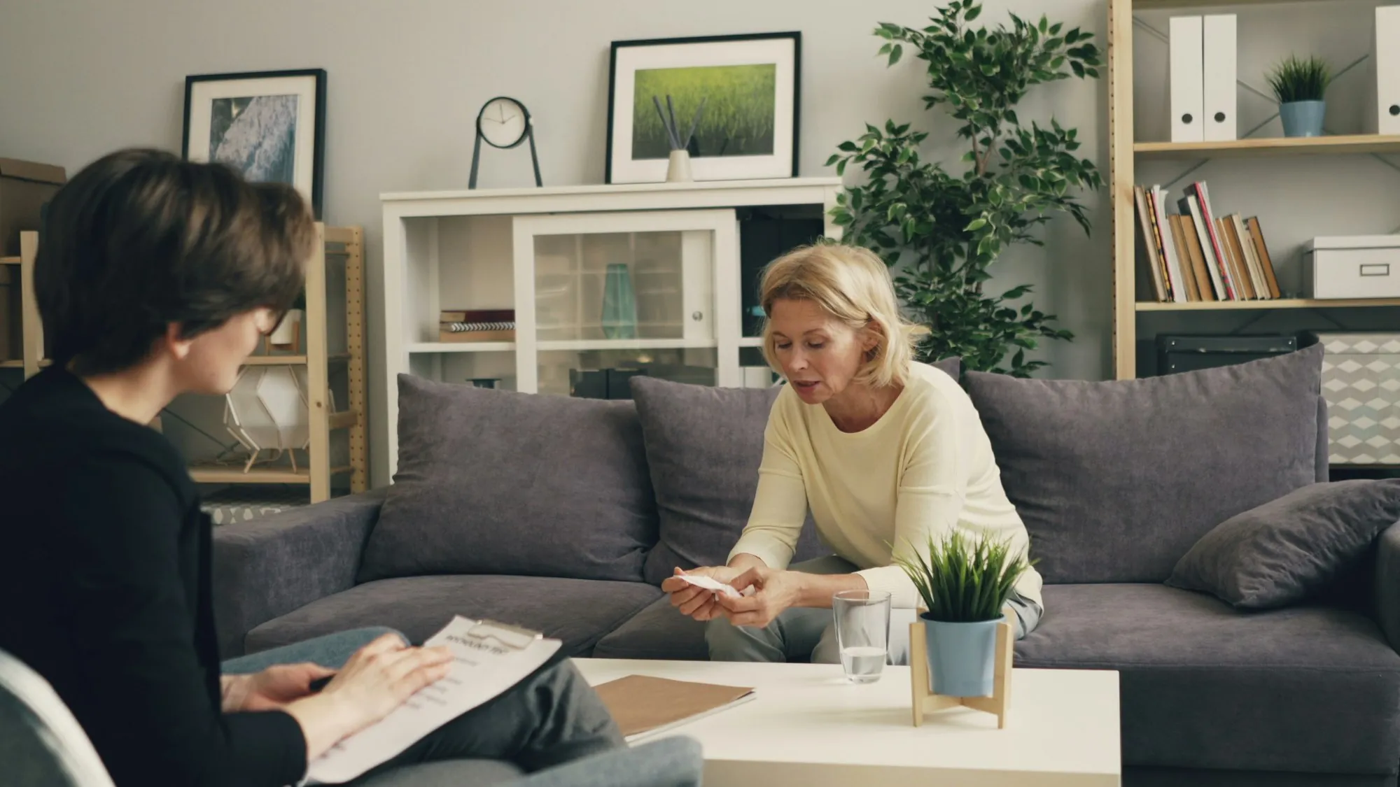 A woman sitting on a sofa talking with another woman