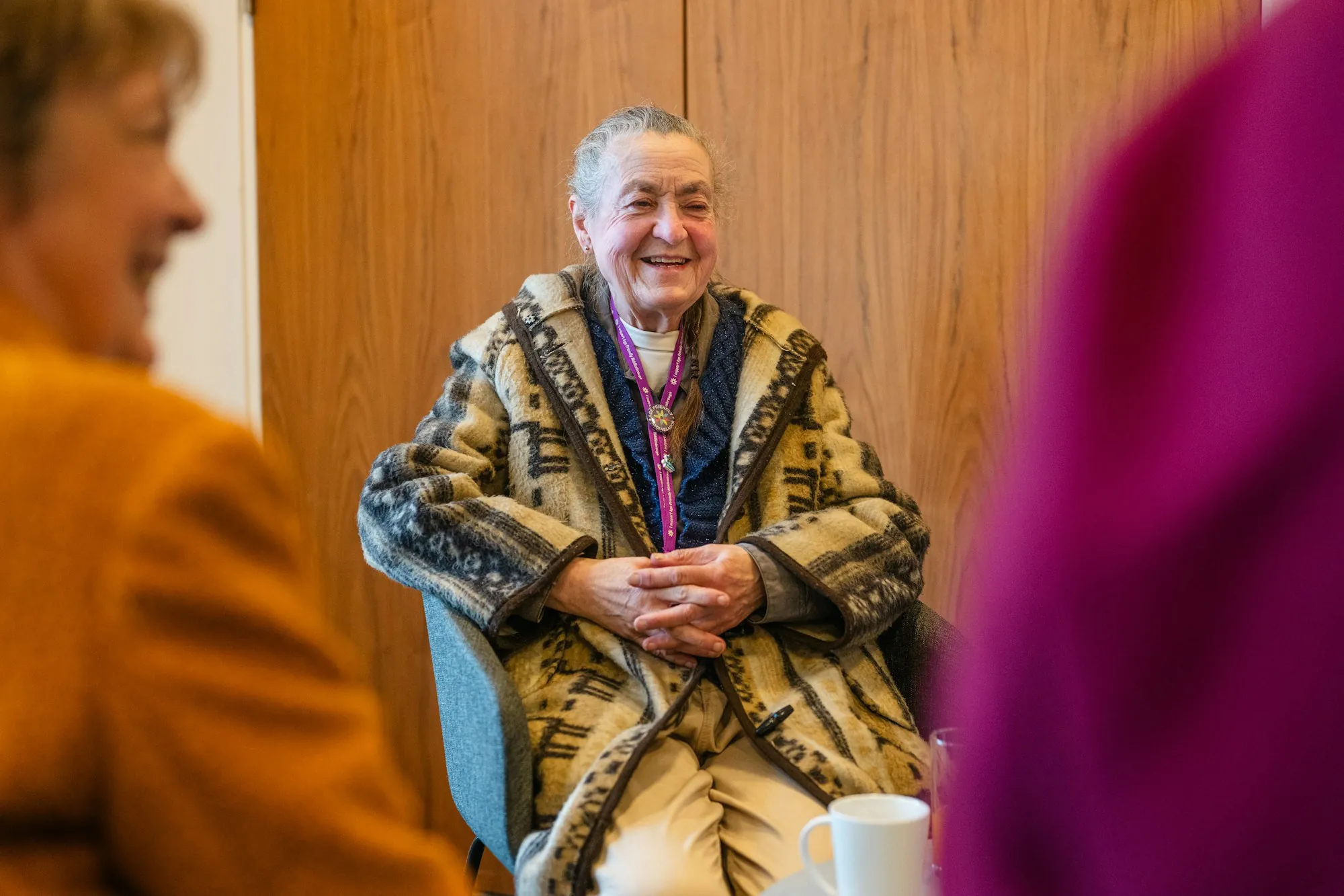 An older woman being helped with a cardigan