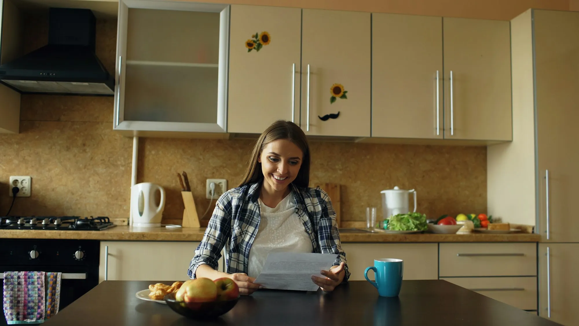 A woman reading a letter at a kitchen table with a cup of coffee